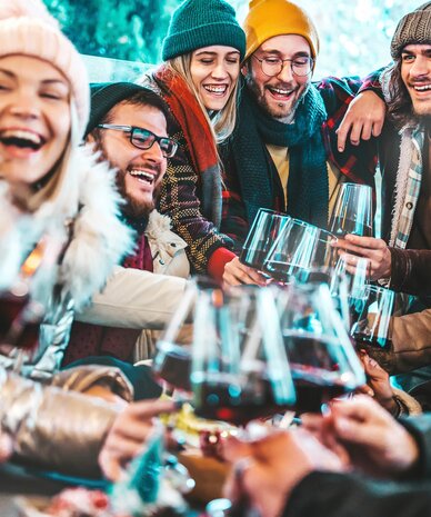 Group of friends toasting with wine glasses outdoors in winter