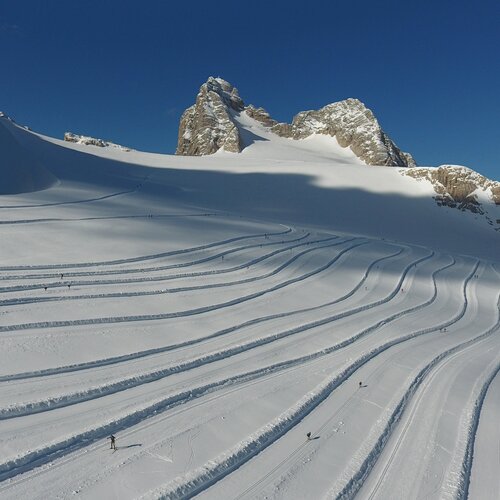 Snowy alpine slope with curving ski tracks and mountains | © photo-austria.at