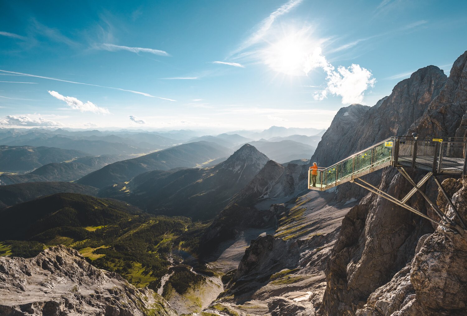 Person on glass viewing platform on a rocky cliff