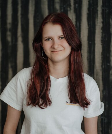 Smiling young woman with long red hair wearing a white t-shirt