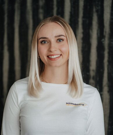 Smiling woman wearing a white shirt with Schladming Apartments logo