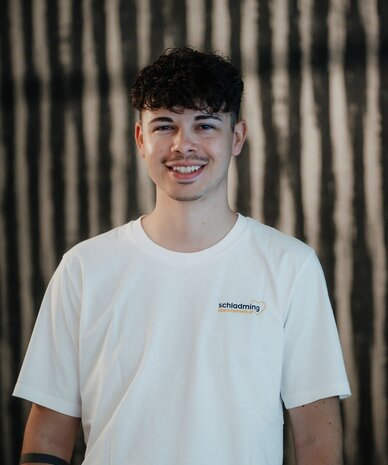 Smiling young man in white T-shirt with schladming logo