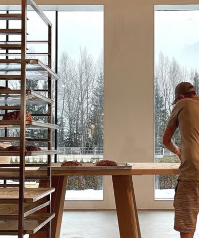 Worker arranges bread on a wooden table in bakery