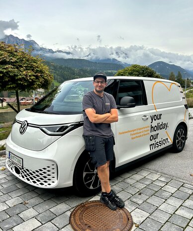 Man beside white van with 'your holiday. our mission' slogan.