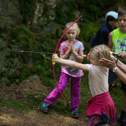 Young girl practicing archery with instructor outdoors