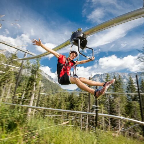 Person riding a zip line on a curved metal track outdoors