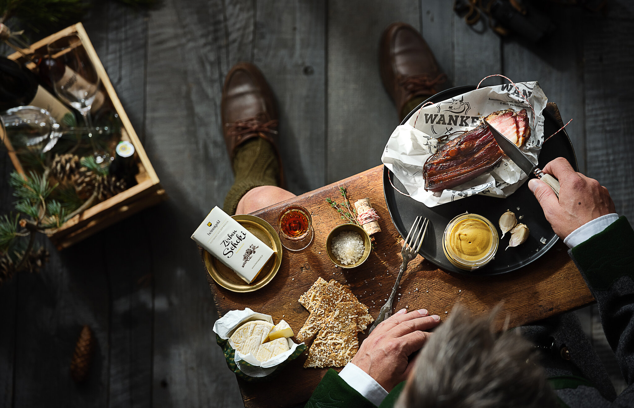 Top-down table with bread, cheese, butter, condiments, and meat plate | © RAPHAELGABAUER.COM