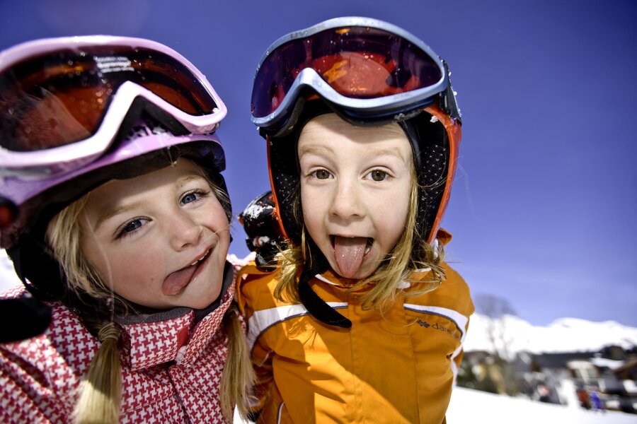 Two children wearing ski helmets and goggles outdoors in snowy landscape | © Tom Lamm
