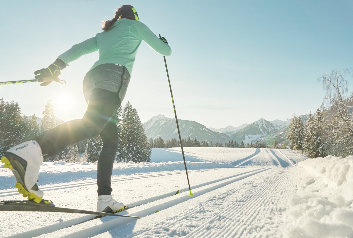 Skier in green jacket gliding on cross-country skis through sunlit snow | © Peter Burgstaller