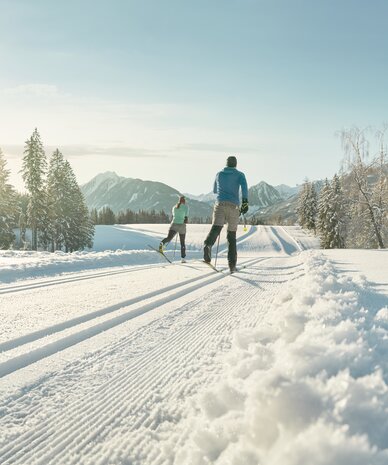 Two skiers cross-country skiing on snow-covered trail in mountains | © Peter Burgstaller