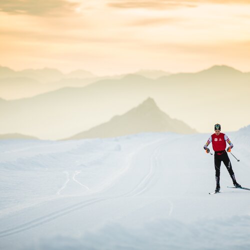 Skier in red vest skiing on snowy slope at sunset | © Photographer: Dominik Steiner