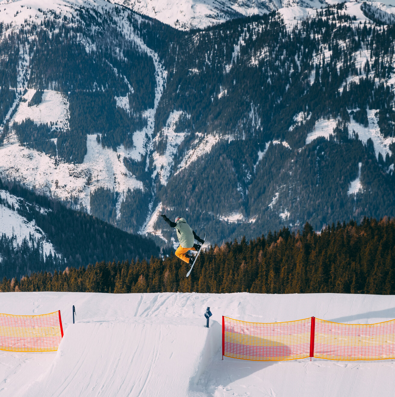 Snowboarder performing an aerial trick over a snowy park jump