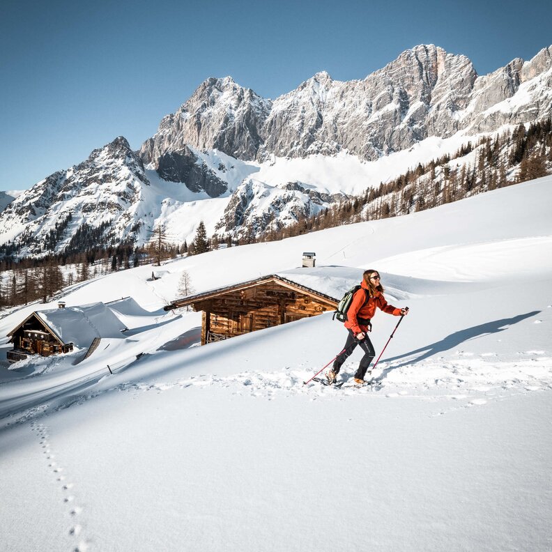 Snowy alpine landscape with hiker and wooden huts