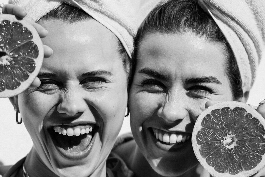 Two women with towels on their heads smiling, holding citrus halves