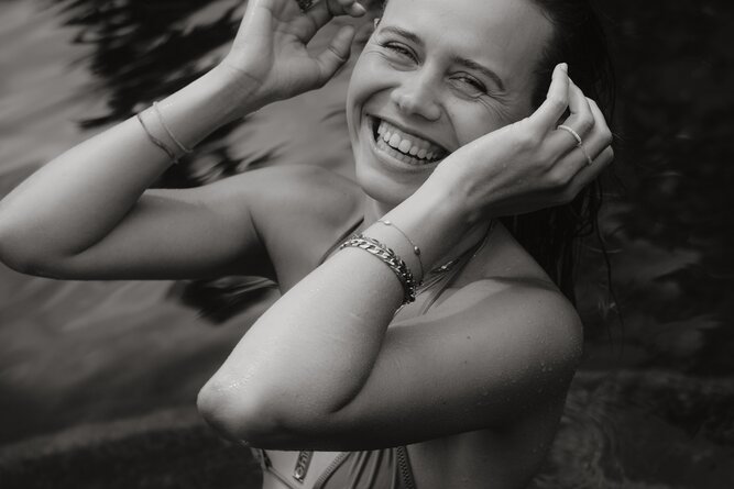 Smiling woman in water, adjusting her hair