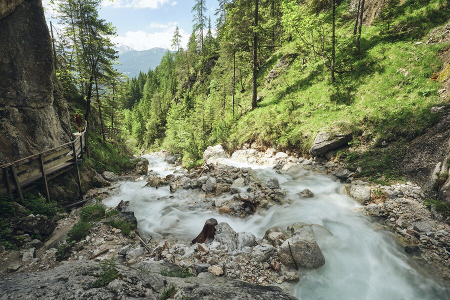 Rushing mountain river in a rocky canyon beside a wooden walkway. | © RAPHAELGABAUER.COM