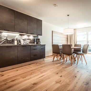 Open-plan kitchen with dark cabinets and dining table