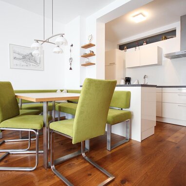 Modern kitchen and dining area with green chairs | © SCHLADMING-APPARTEMENTS