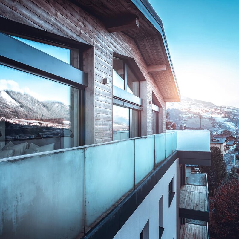 Modern wooden building with glass balcony overlooking snowy town