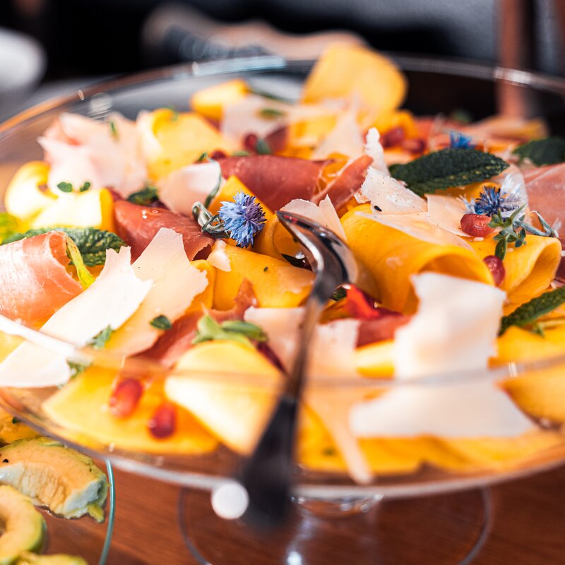 Colorful fruit and prosciutto salad in glass bowl | © TIEBER