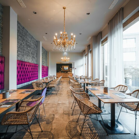 Chic restaurant interior with purple tufted seating and chandeliers | © TIEBER