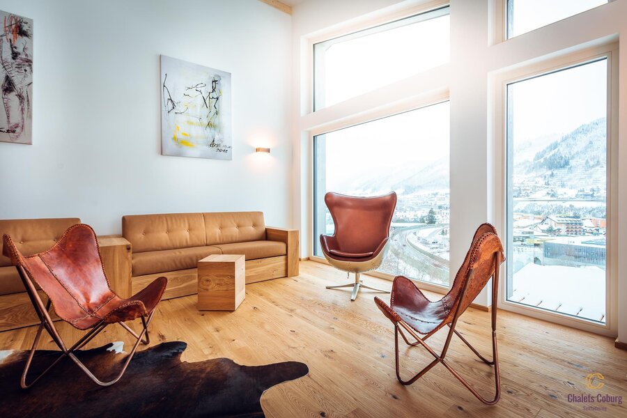 Bright living room with leather chairs and large windows overlooking snowy mountains