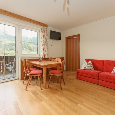 Living room with red sofa and dining table overlooking mountains
