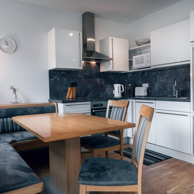 Modern kitchen with white cabinets, dark marble backsplash, and dining table