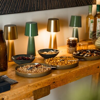 Wooden table with bowls of assorted nuts and bottles