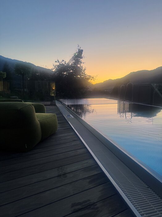 Infinity pool beside wooden deck at sunset