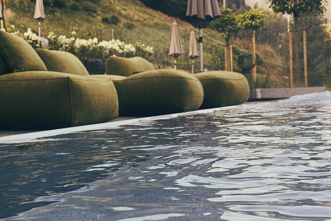 Poolside area with green curved couches and umbrellas