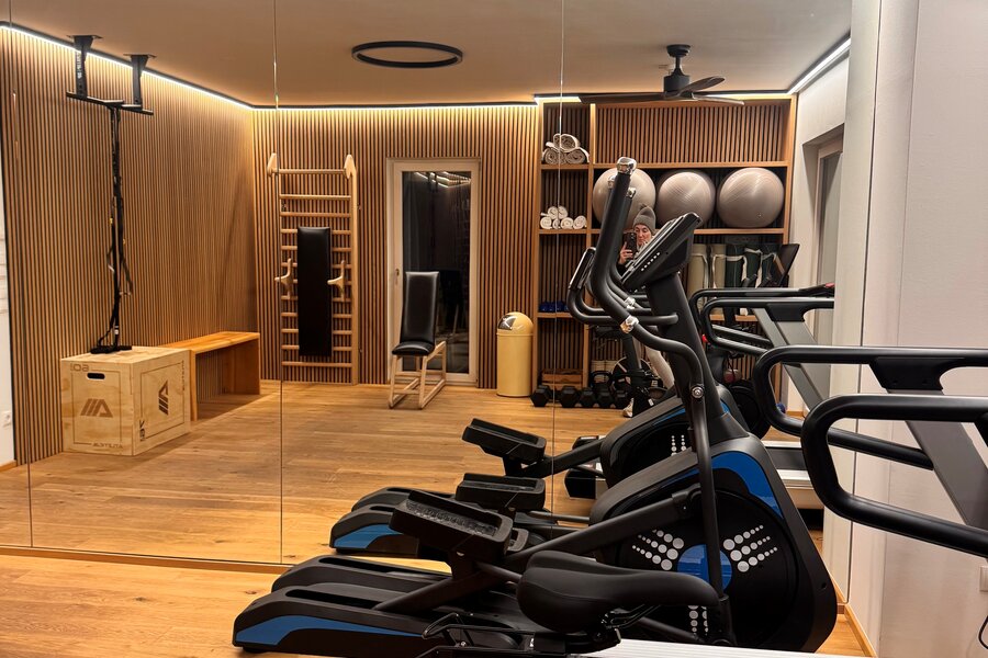 Row of treadmills and bikes in wood-paneled gym.