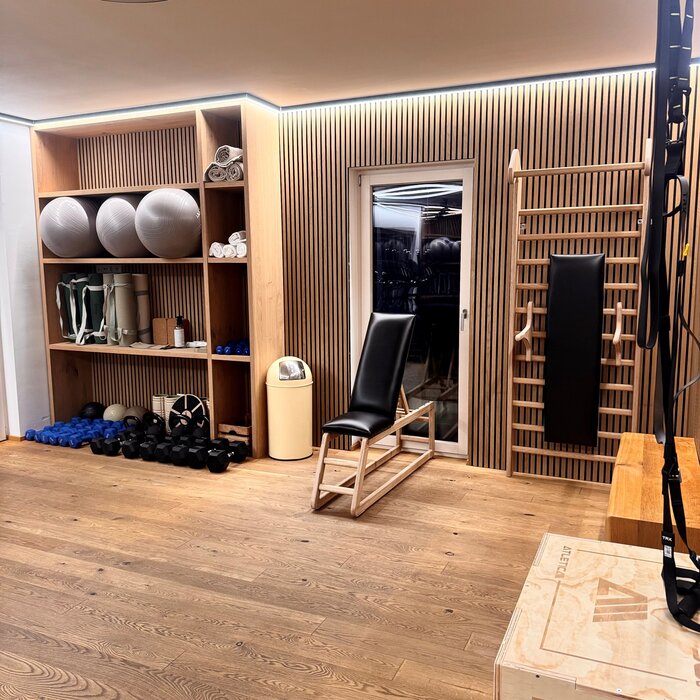 Gym corner with wooden wall panels, weight rack, chair