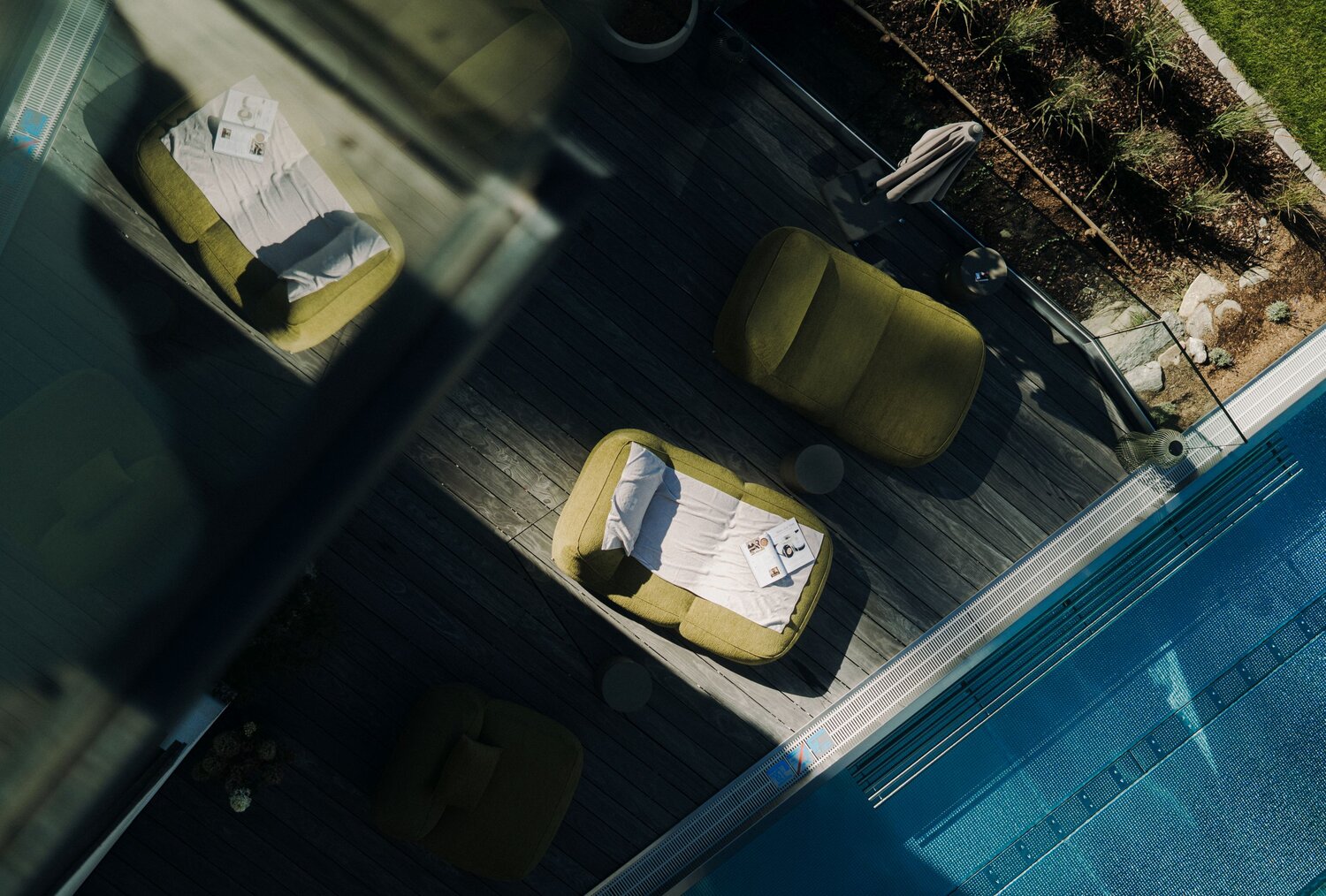 Aerial view of poolside deck with green lounge chairs and magazines