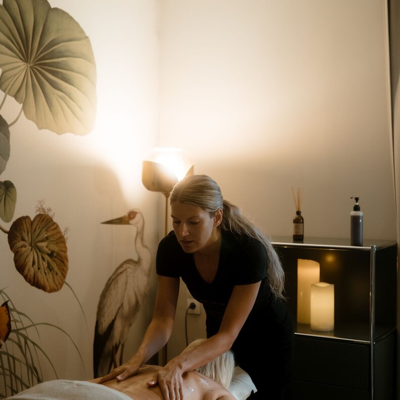Massage therapist performs back massage on client in calm spa room