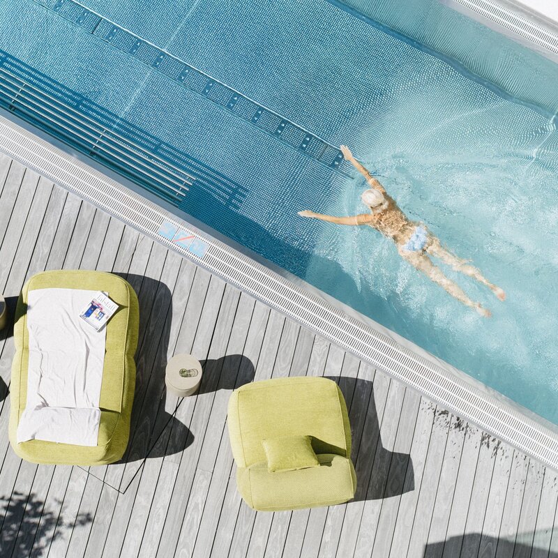 Overhead poolside deck with lime lounge chairs and a swimmer.