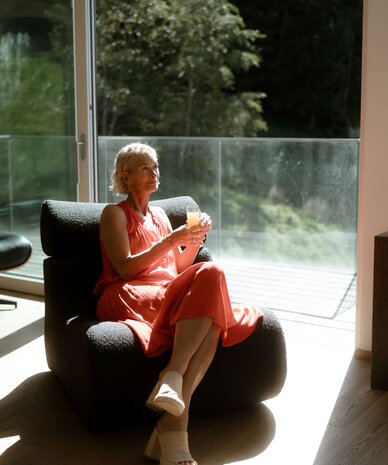 Older woman relaxing on a sofa with a drink
