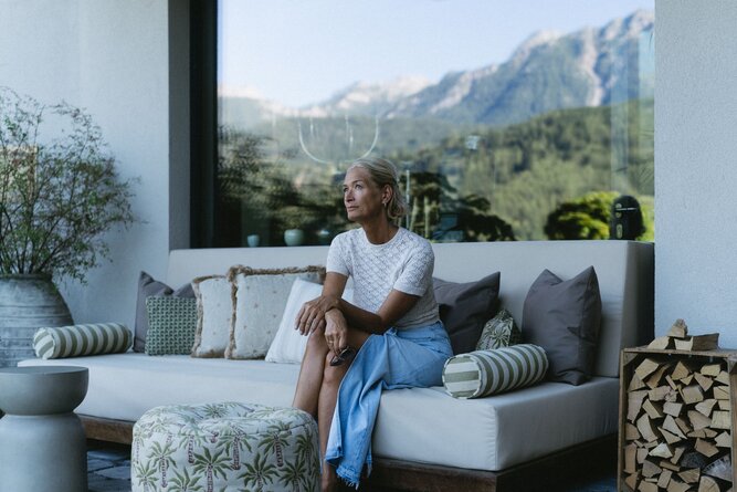 Woman sits on outdoor sofa with mountain view