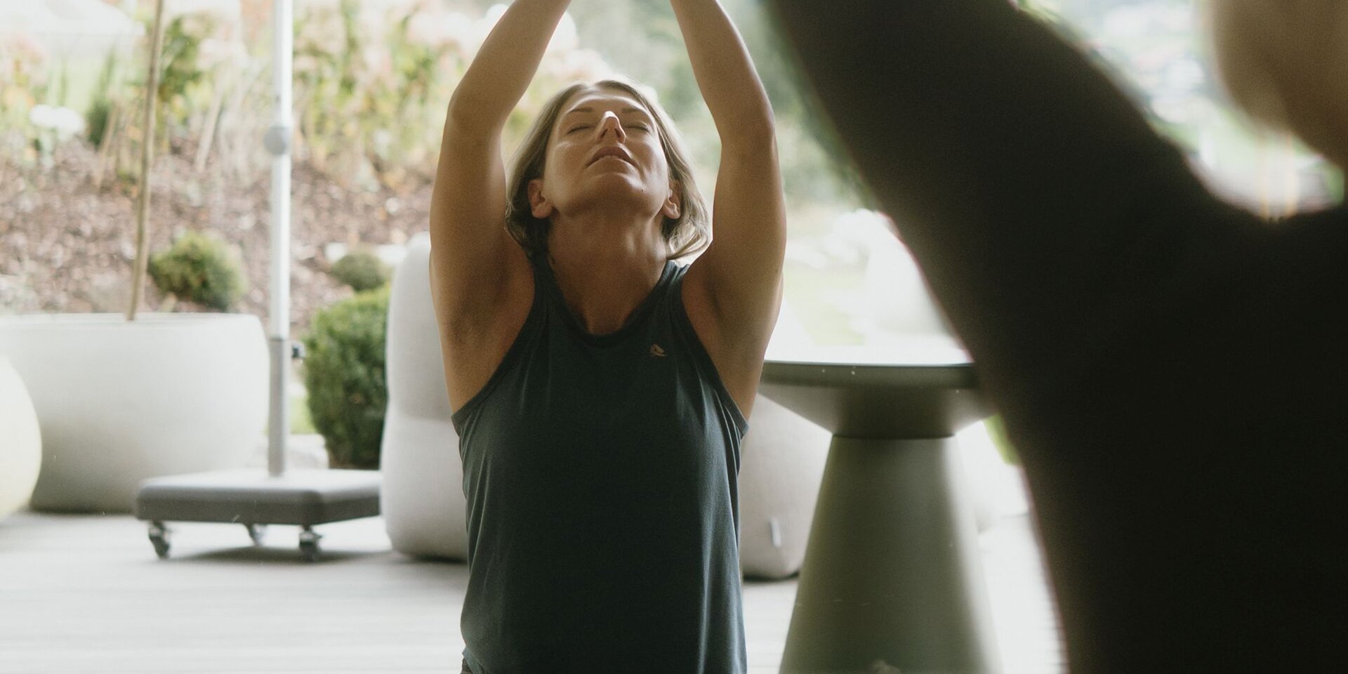 Woman practicing seated yoga indoors with hands raised