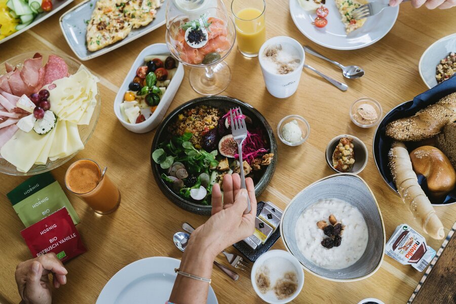 Overhead view of varied breakfast spread with cheese, bread, salad
