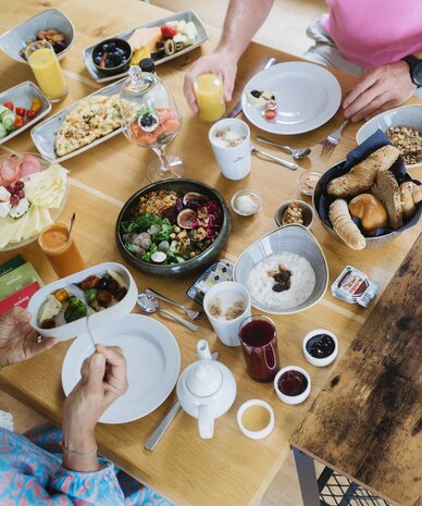 Large wooden table loaded with breakfast items and drinks
