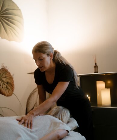 Massage therapist giving back massage to client on table