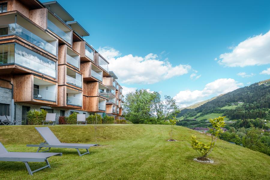 Modern wooden apartment building with glass balconies on hillside
